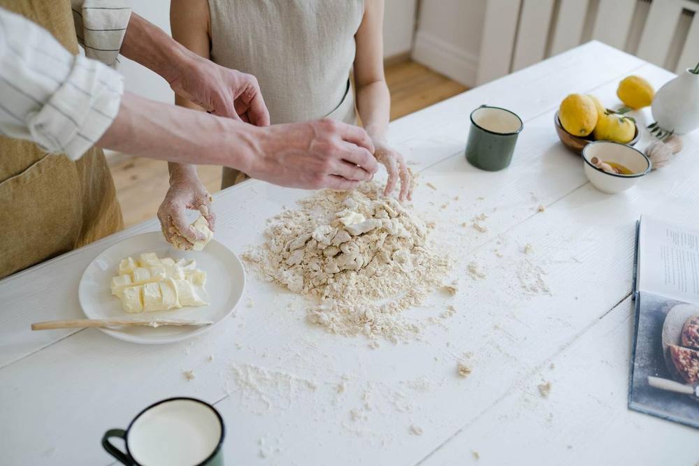 Two people making pasta dough on a floured table
