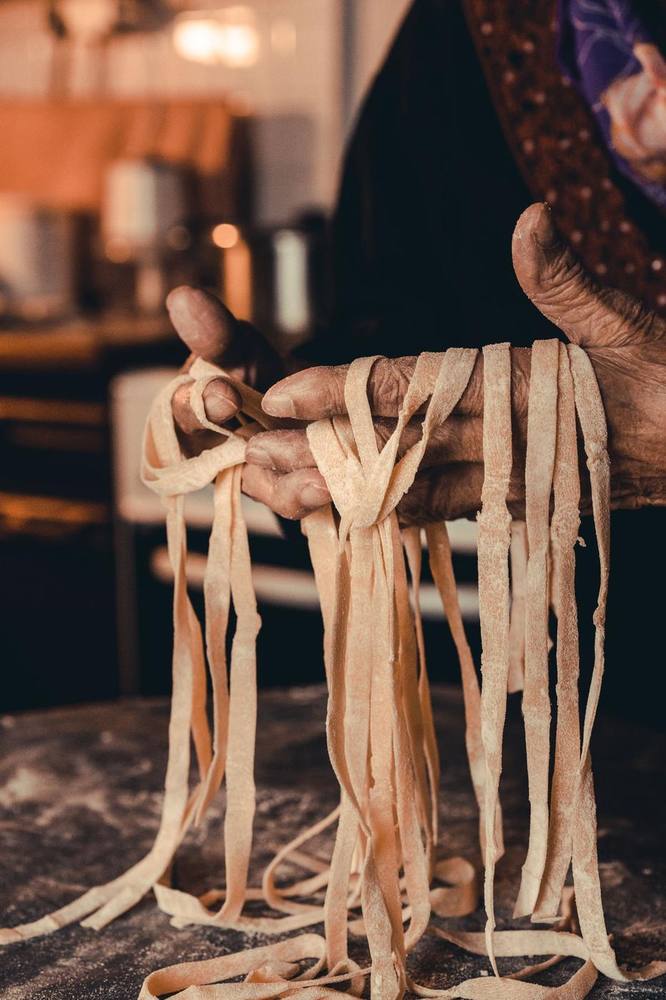 Hands holding freshly cut ribbons of pasta